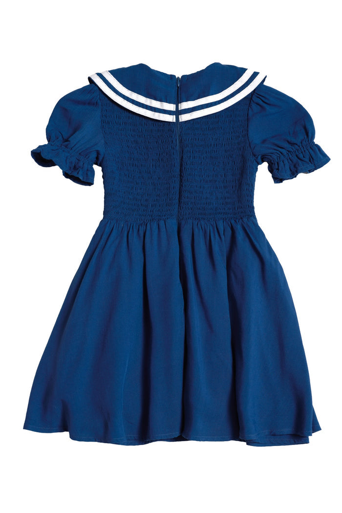 The Mini Alice Dress in Navy by Ivy City Co features short ruffled sleeves, a fitted smocked bodice, flared skirt, and sailor collar with white stripes. Perfect for Mom and Me matching looks. Shown on a white background.