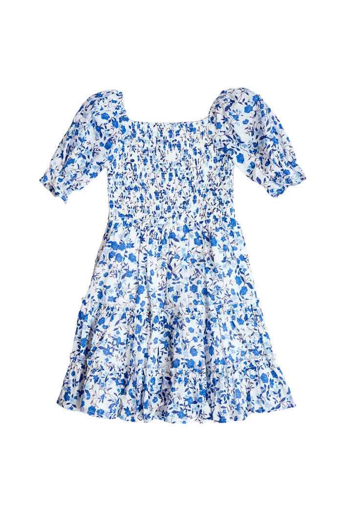 The Mini Madeline Dress in Ditsy Cobalt Floral by Ivy City Co features a white base with cobalt floral print, puffed short sleeves, smocked bodice, and ruffled hem—ideal for matching "Mom and Me" moments. Shown on a white background.