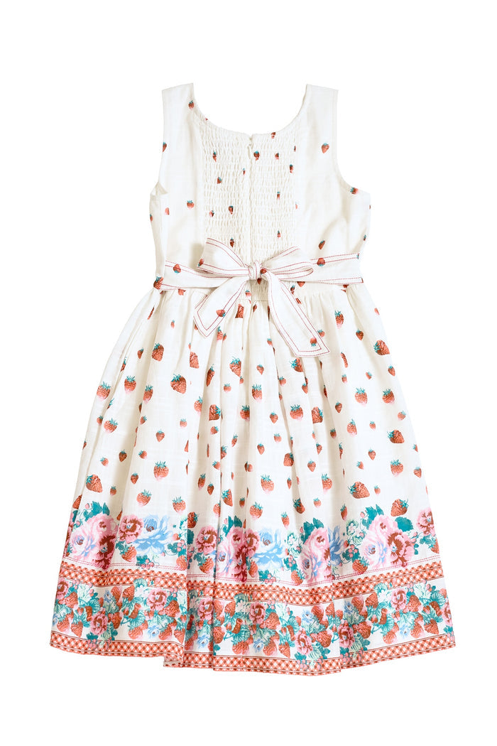 The Mini Sadie Dress in Strawberry Vintage Tier by Ivy City Co is a sleeveless white cotton children's dress with strawberry prints, a pink and white waist tie, tiered design, and colorful floral and checkered hem borders.