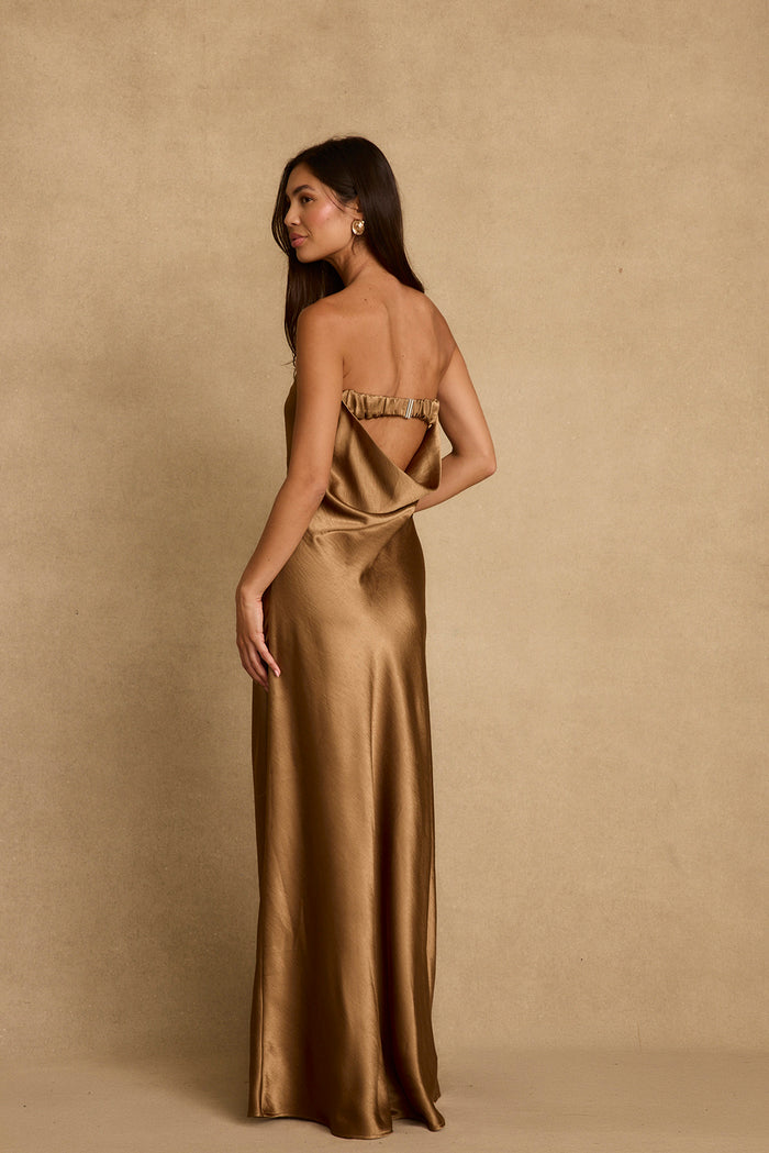 Open back of the Natalia bronze satin maxi dress, shown on-model against tan backdrop.