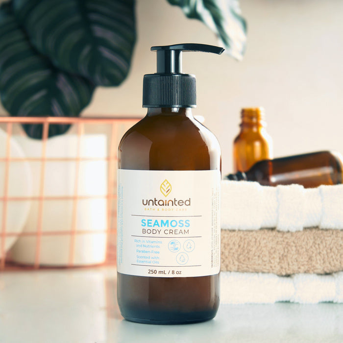 Natural Scented Sea moss BodyCream _ FrontSide _ on top of a bathroom counter with empty bottle in the background of spa
