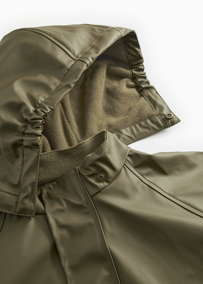 Close-up of a green raincoat: hood and reinforced seam with pressure buttons at the opening