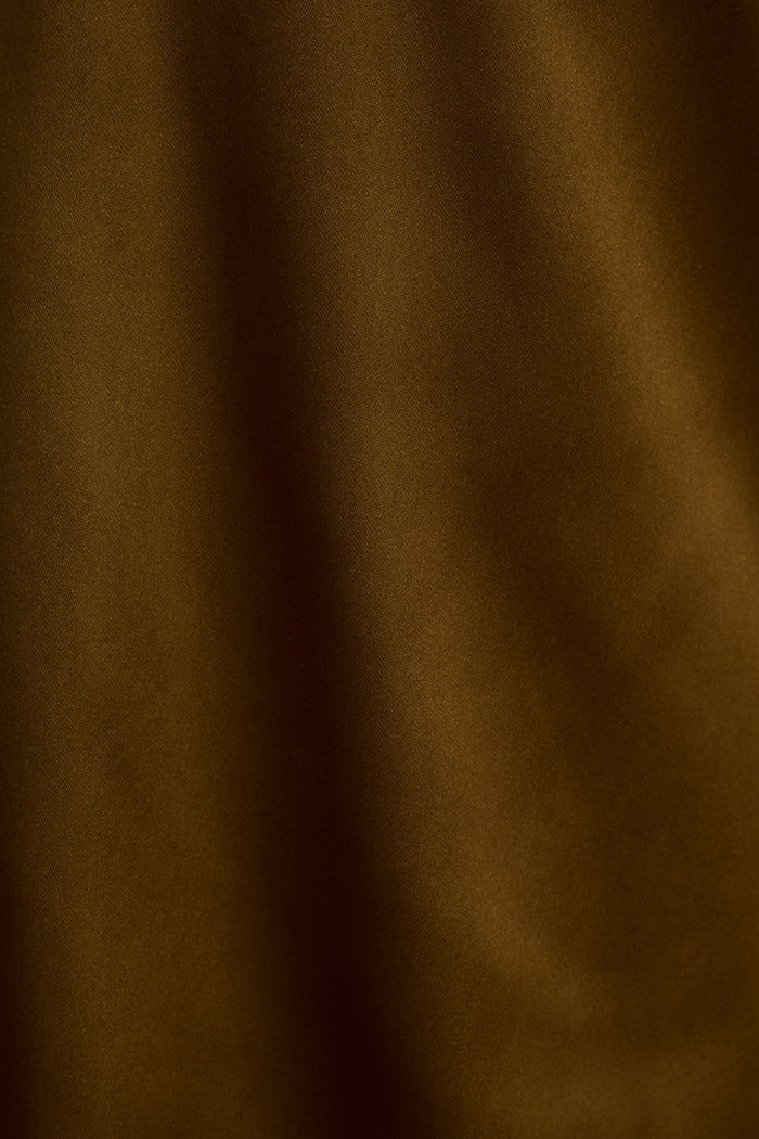 Extreme close-up of the olive satin trousers fabric, showing soft sheen and gentle folds.