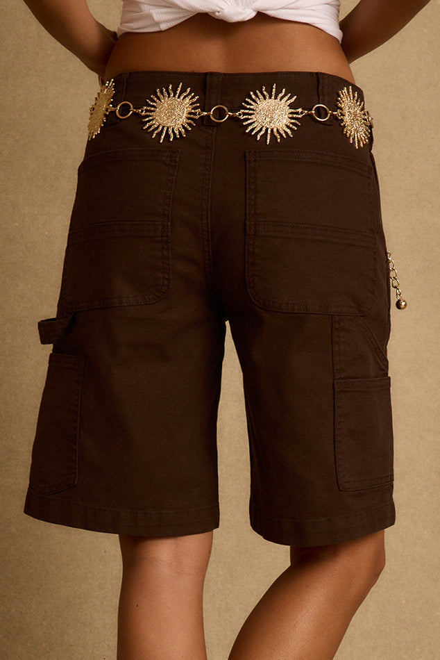 Back view of mocha longline cargo shorts with patch pockets and gold sun chain belt.