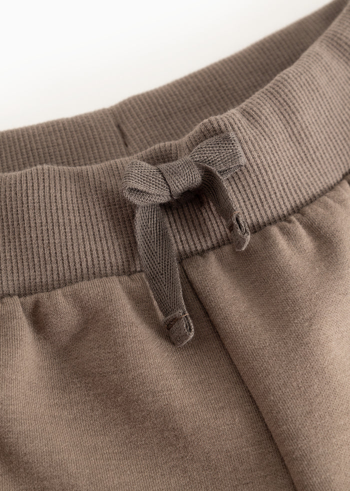 Dusty brown pants: elastic waistband with adjustable drawstring and visible stitching.