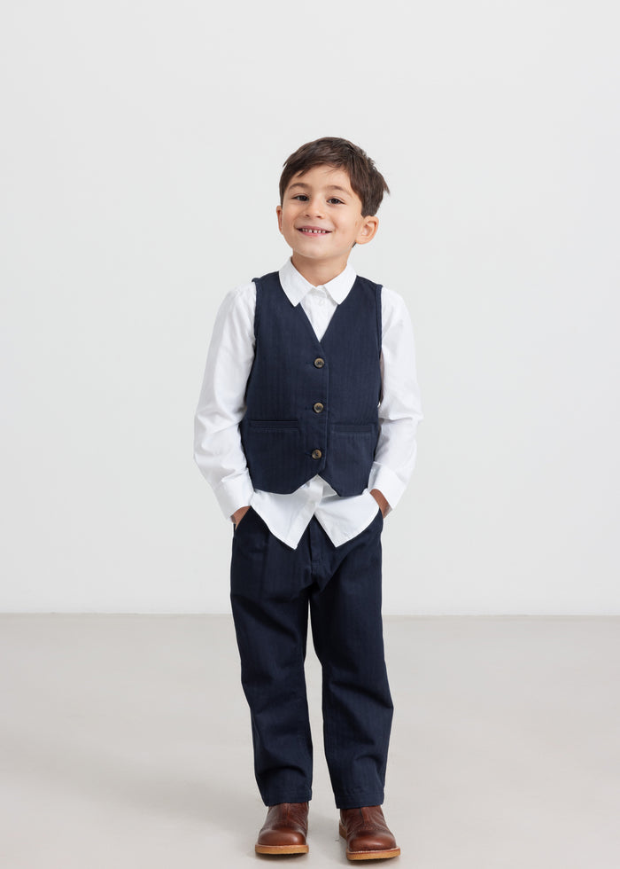 Boy wearing party clothes - dark blue pants, white shirt and vest for children