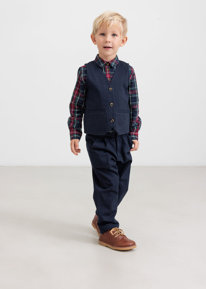Boy wearing dark blue pants and checkered shirt in a Christmas look for children