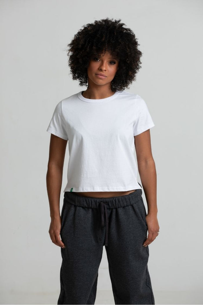 Person wearing a white t-shirt and dark pants on a plain background || white