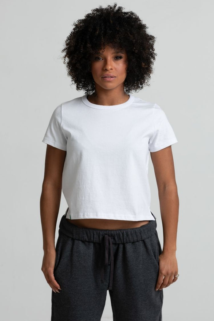 Person wearing a white t-shirt and dark gray pants on a plain background || white