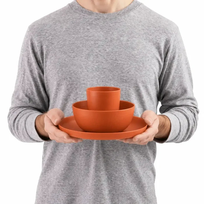 Person holding a Sea To Summit Camp Dinnerware Set against a white background