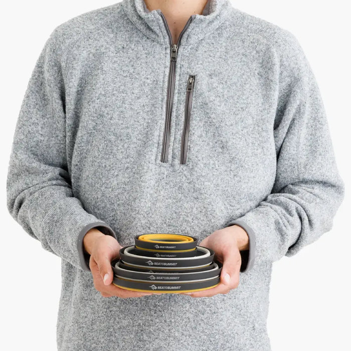 Person holding a set of nestled and collapsed Sea To Summit dinnerware 6 piece set on a white background