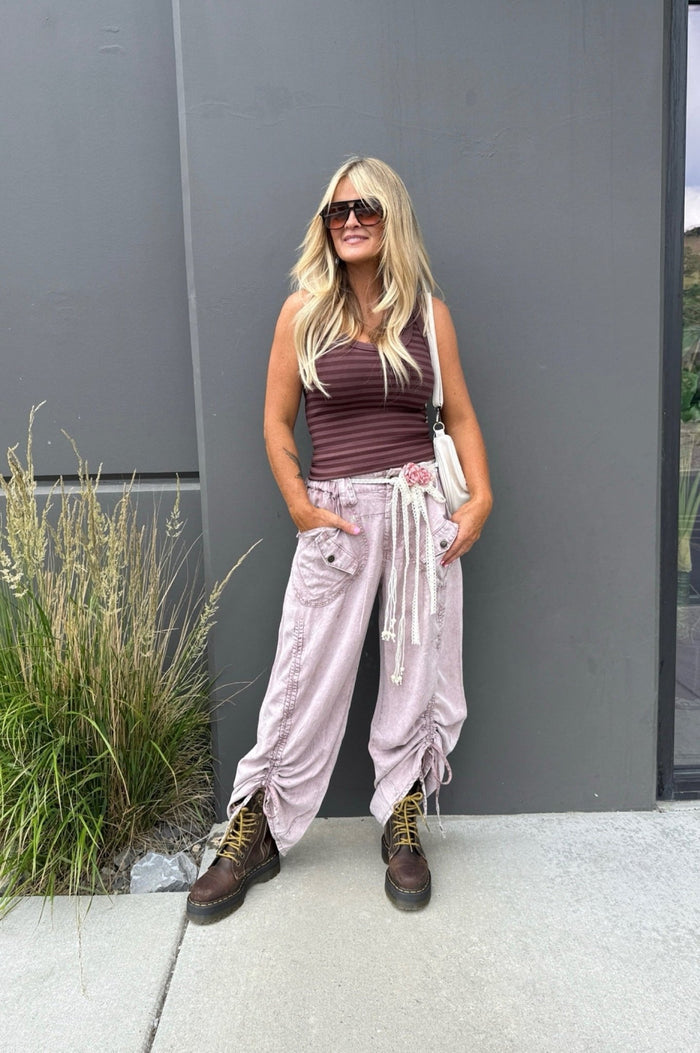 Dusty blush bohemian pants with drawstring waist, oversized pockets, and adjustable gathered hems styled with combat boots for a relaxed boutique boho outfit.