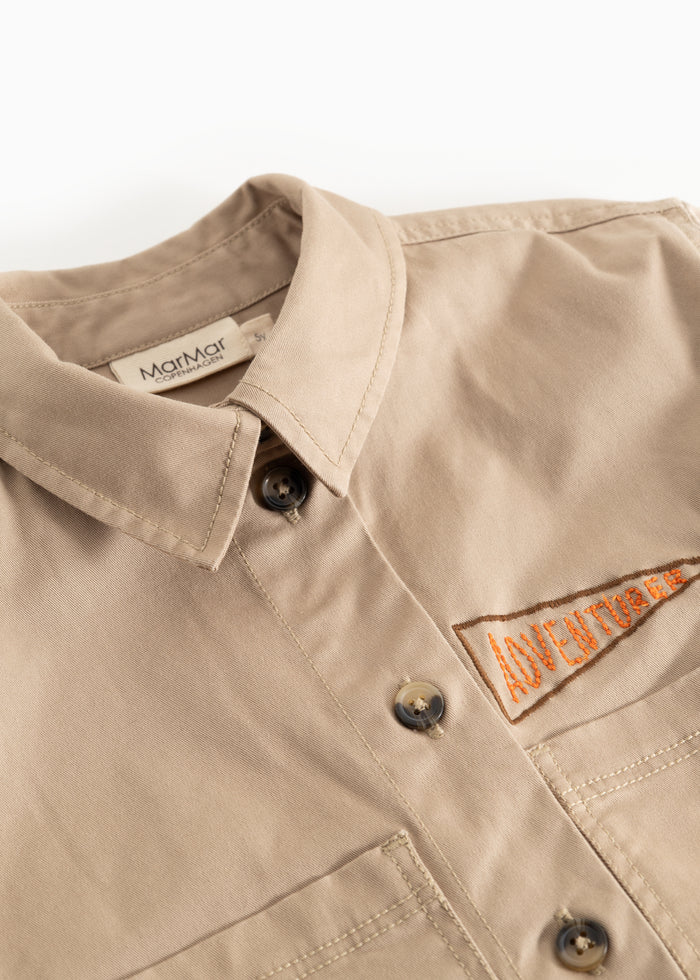 Beige jacket for children with snap closure and logo patch on the chest.