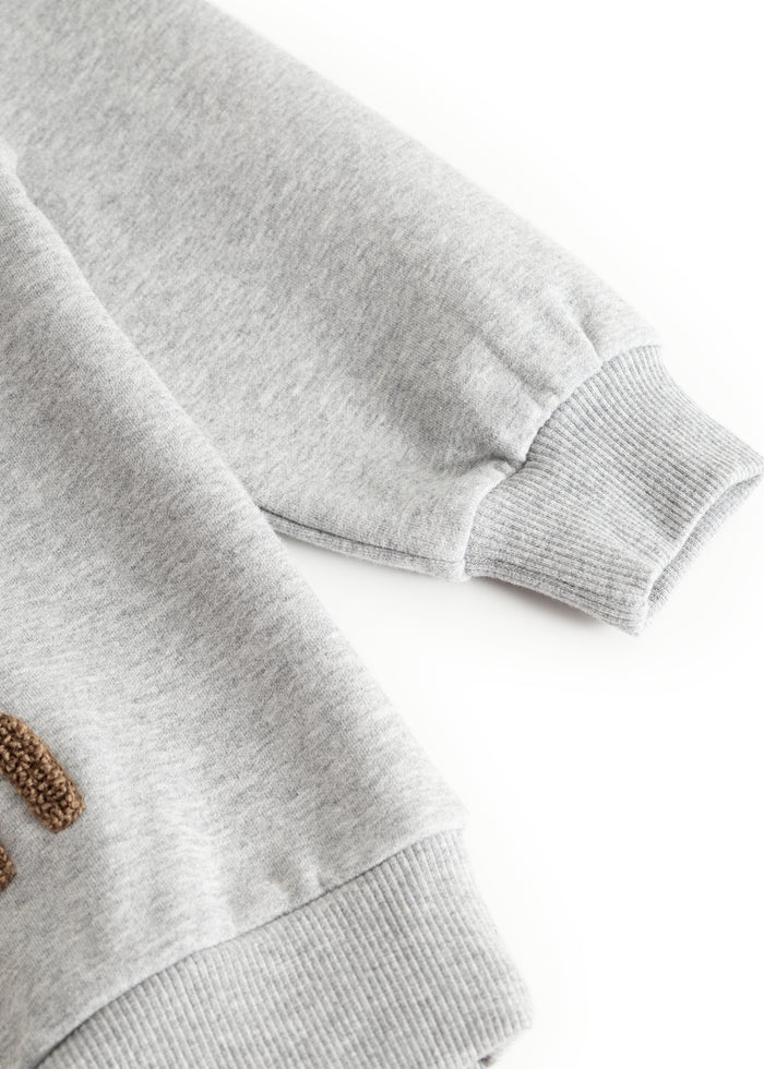 Gray sweatshirt with ribbed cuff at the sleeve ending and visible seam.