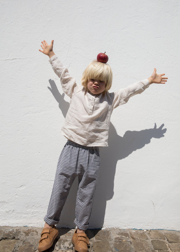 Child wearing a beige shirt and netted pants.