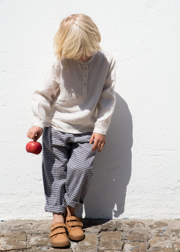 Child wearing a beige shirt and netted pants.