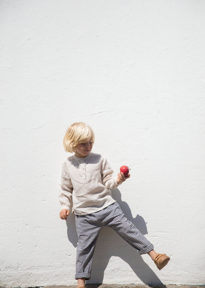 Child wearing a beige shirt and netted pants.
