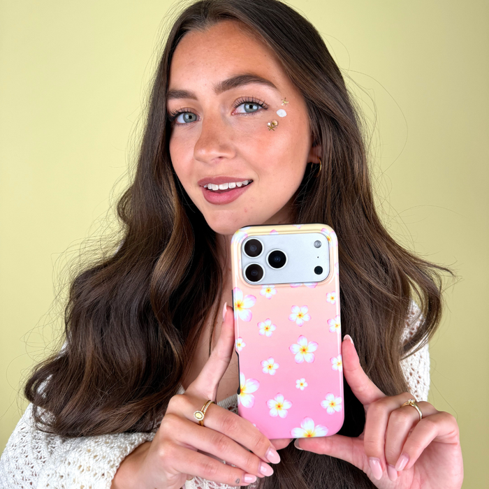 Woman holding a phone with a pink floral case against a yellow background