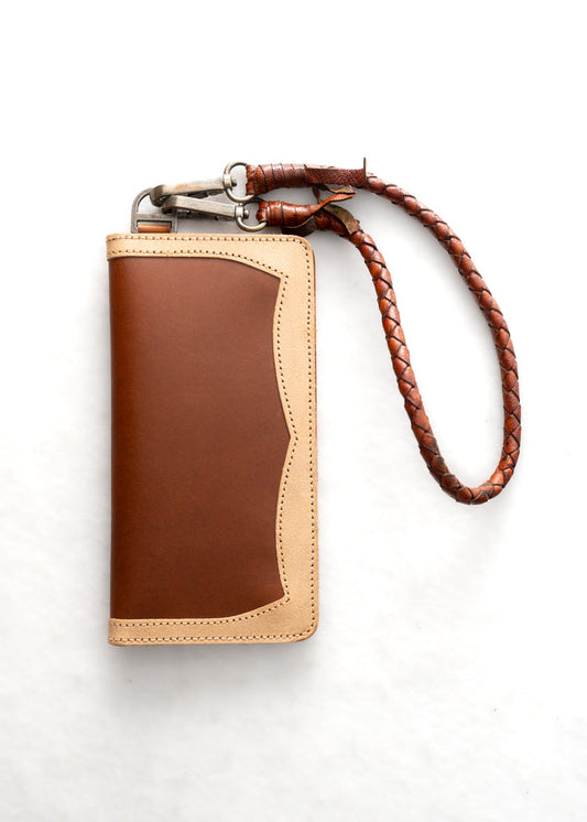 Brown leather wallet with beige trim and braided strap, featuring a metal clasp, on a white background.