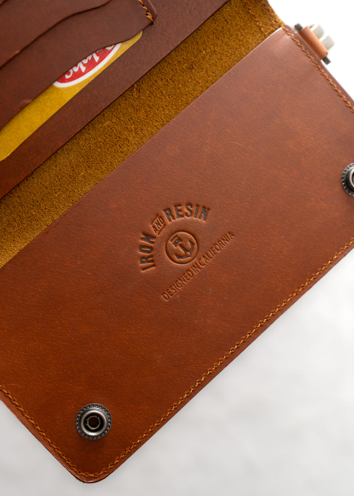 Open brown leather wallet with "Iron and Resin" embossed, showing card slots and snap buttons, designed in California.