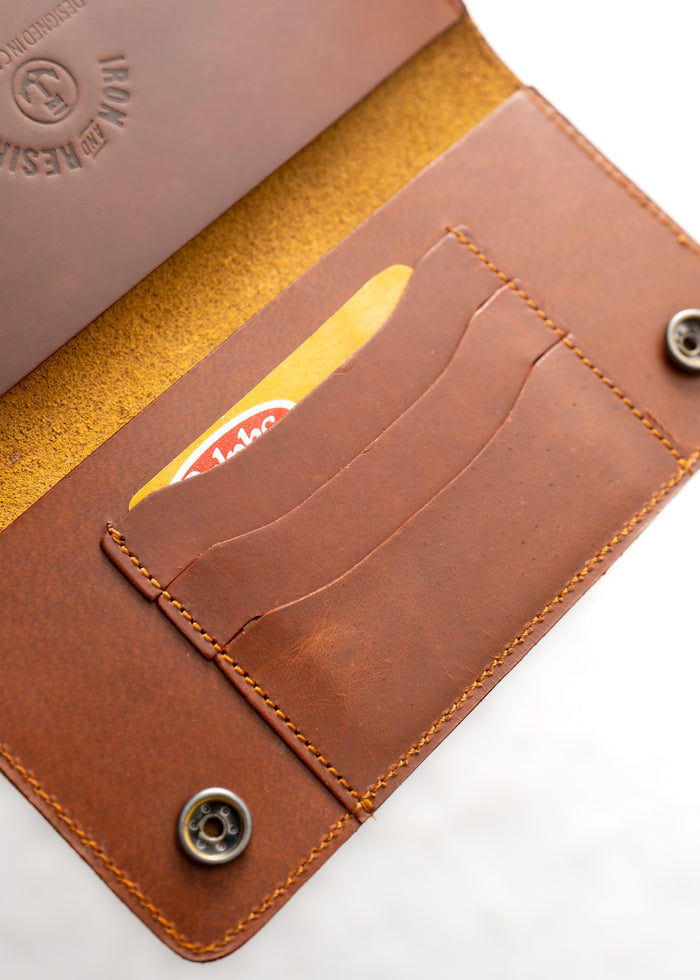 Open brown leather wallet with visible card slots and snap buttons, showcasing craftsmanship and texture.