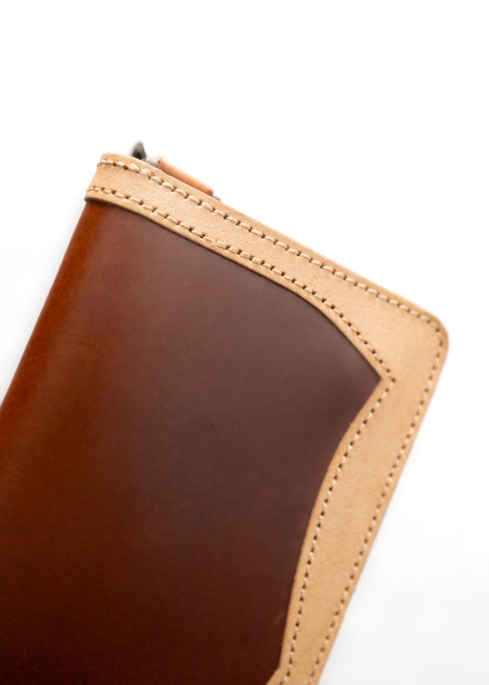 Close-up of a brown leather wallet with beige stitching on a white background, showcasing craftsmanship and texture.