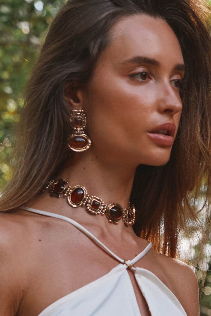 Villa Amber choker and matching drop earrings worn with a white halter top outdoors.