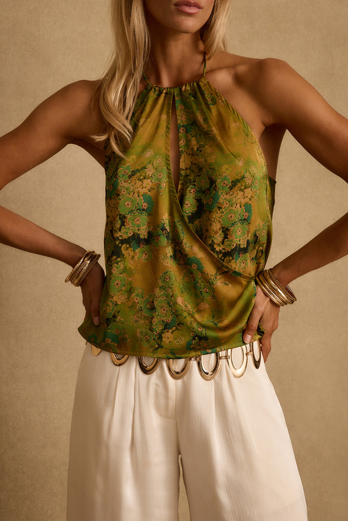 Close-up of chartreuse floral satin halter top with keyhole detail, styled with cream trousers.
