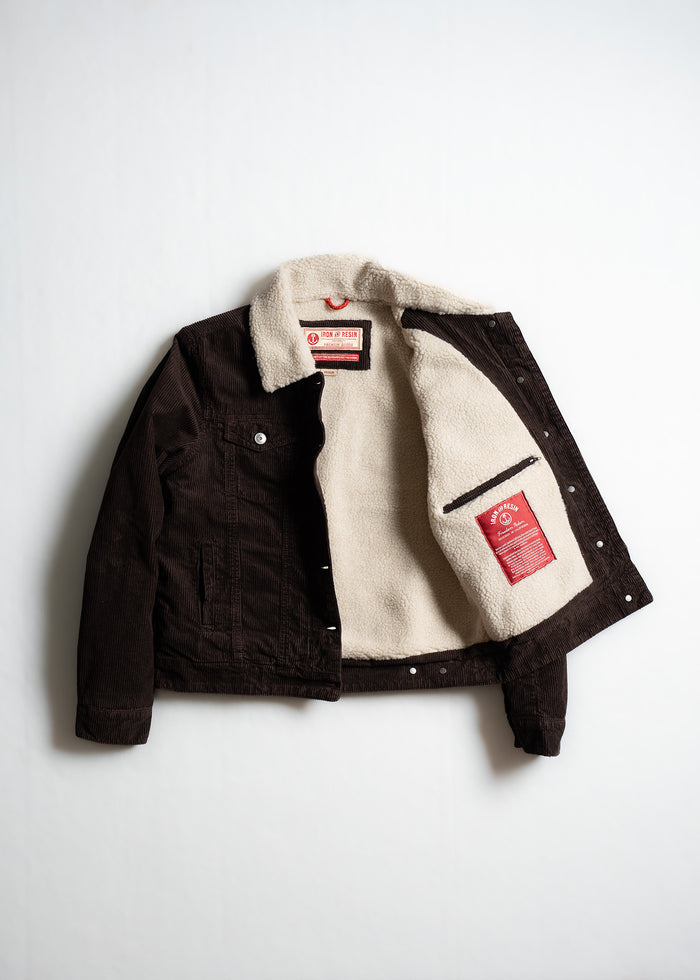 Brown corduroy jacket with a white fleece lining, open to reveal a red label inside, displayed on a plain white background.