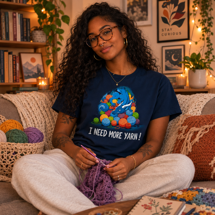 Premium Cotton T-shirt_TeeTurtle Yarn Hoarder navy blue t-shirt featuring a blue dragon sitting on top of a pile of multi-colored yarn balls. The words "I NEED MORE YARN!" are written underneath the illustration.