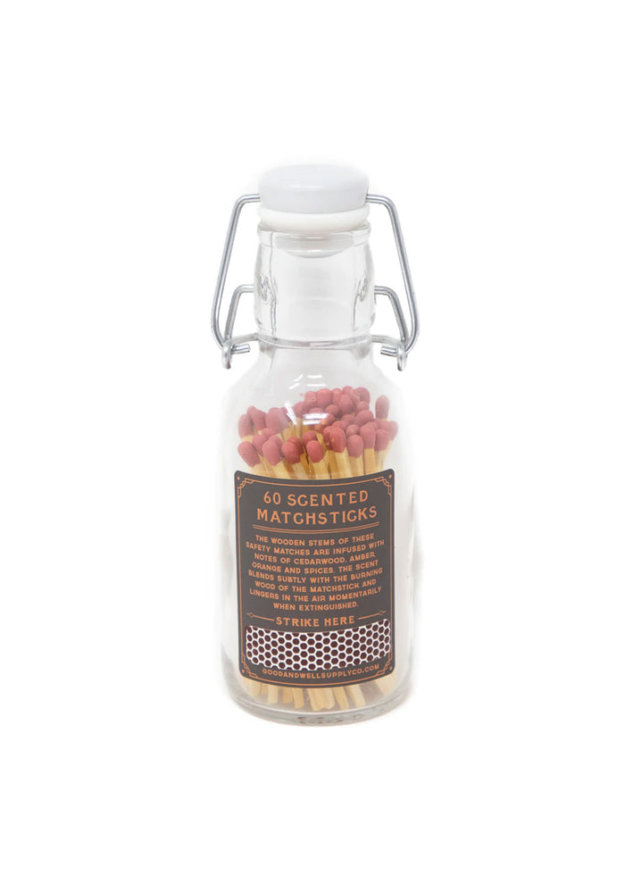 Glass jar with 60 scented matchsticks, red tips, and a label detailing cedarwood, amber, and spice notes.